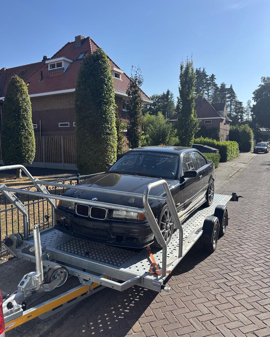 Zwarte BMW E36 met rolkooi op de aanhanger