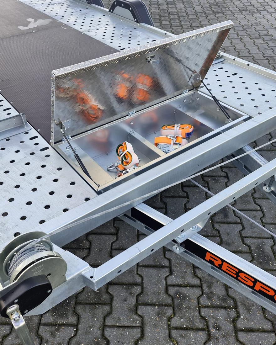 Geopende gereedschapskist op de aanhanger met oranje wielspanbanden