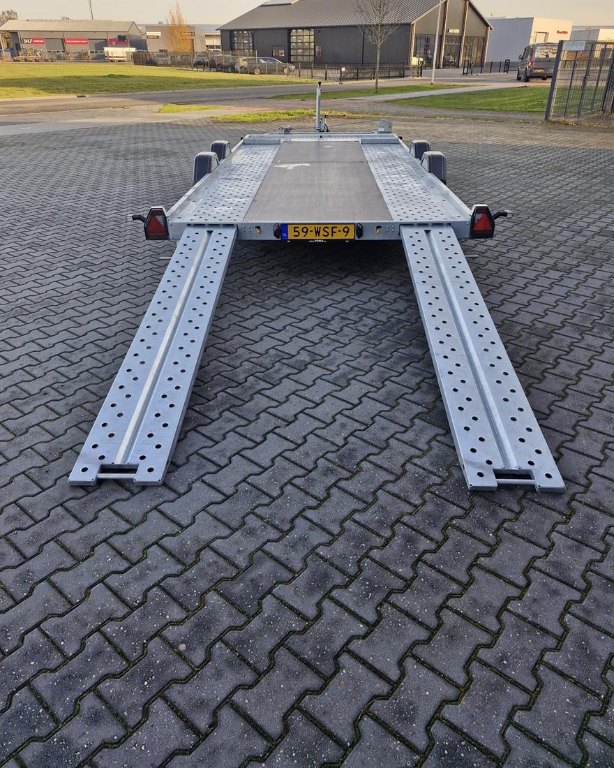 De aanhanger van achteren met twee lange, uitgeschoven oprijplaten